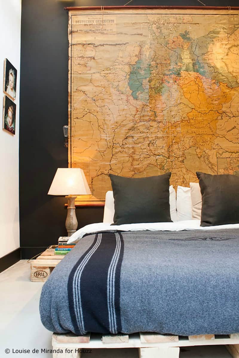 SIMPLE PALLET BED FRAME WITH A LARGE VINTAGE MAP SERVING AS ITS BACKGROUND