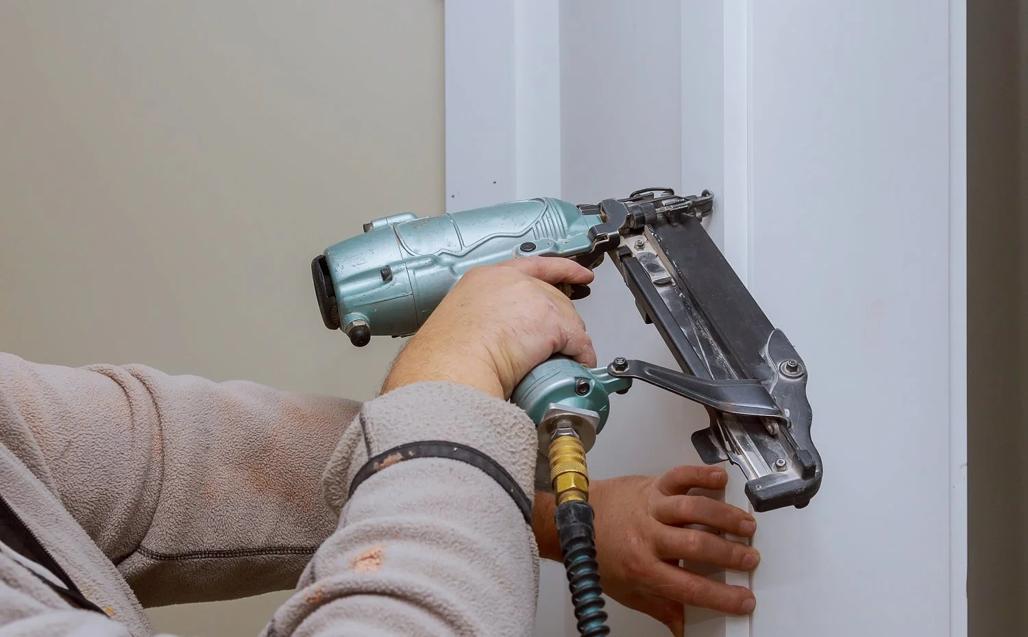 Construction handyman is working on renovation of apartment using air nail gun