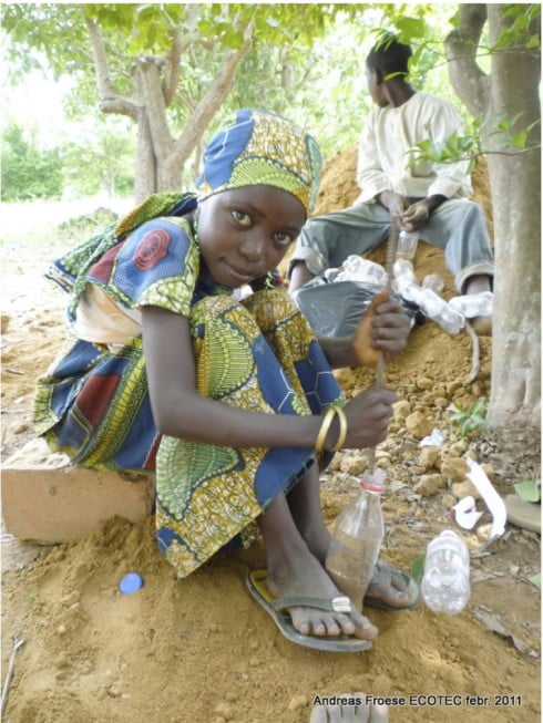 african child working on Experimental Living- Sustainable Plastic Bottle House by D.A.R.E (1)