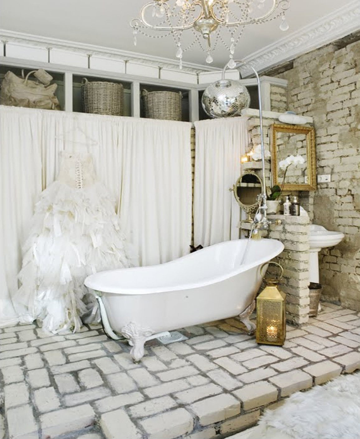 vintage-bathroom-theme-idea-with-brick-wall-and-floor-and-clawfoot-tub-and-crystal-chandelier-and-white-curtains-and-baskets