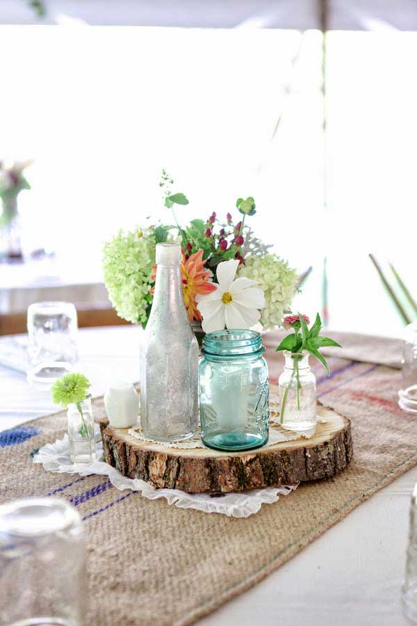 #7 One Slice of Wood Carrying a Mason Jar and Various Flowers in The Perfect Wedding Centerpiece