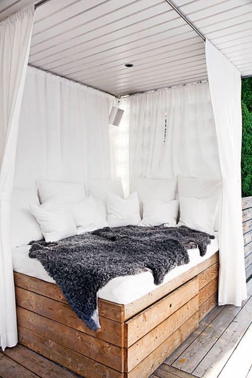 #6 Picture building a daytime canopy pallet bed covered in throw pillows with white open curtains
