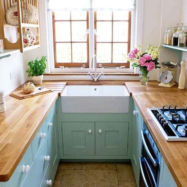 Wood counter-tops on teal furniture nestled between white walls.