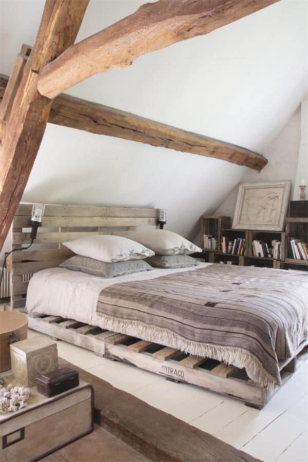  PALLET BED FRAME NESTLED IN A SMALL ATTIC BEDROOM WITH EXPOSED BEAMS