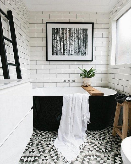 Beautiful black and white bathroom with white subway tiles black grout graphic geometric patterned floor black freestanding bathtub and modern fine art photography