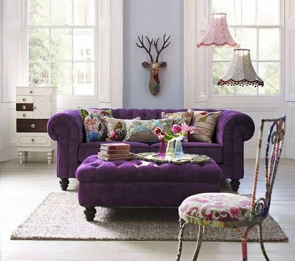 violet chesterfield sofa with ottoman as coffee table and floral cushions