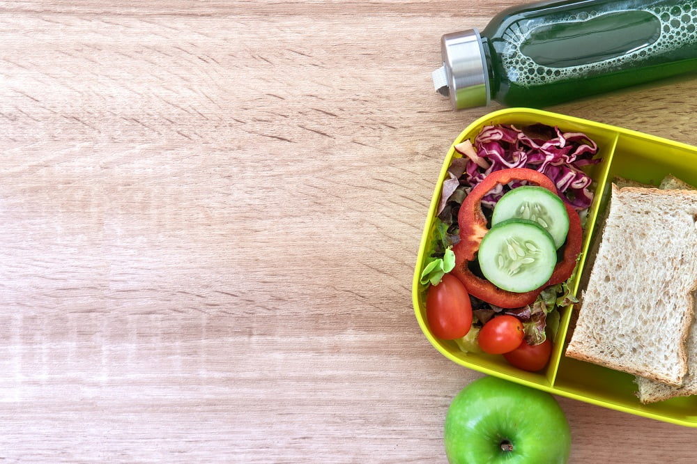 Healthy Lunch box with grain bread and green vegetable and fruit juice bottle on wooden background ,Healthy eating clean food habits for diet concept , top view and overhead shot