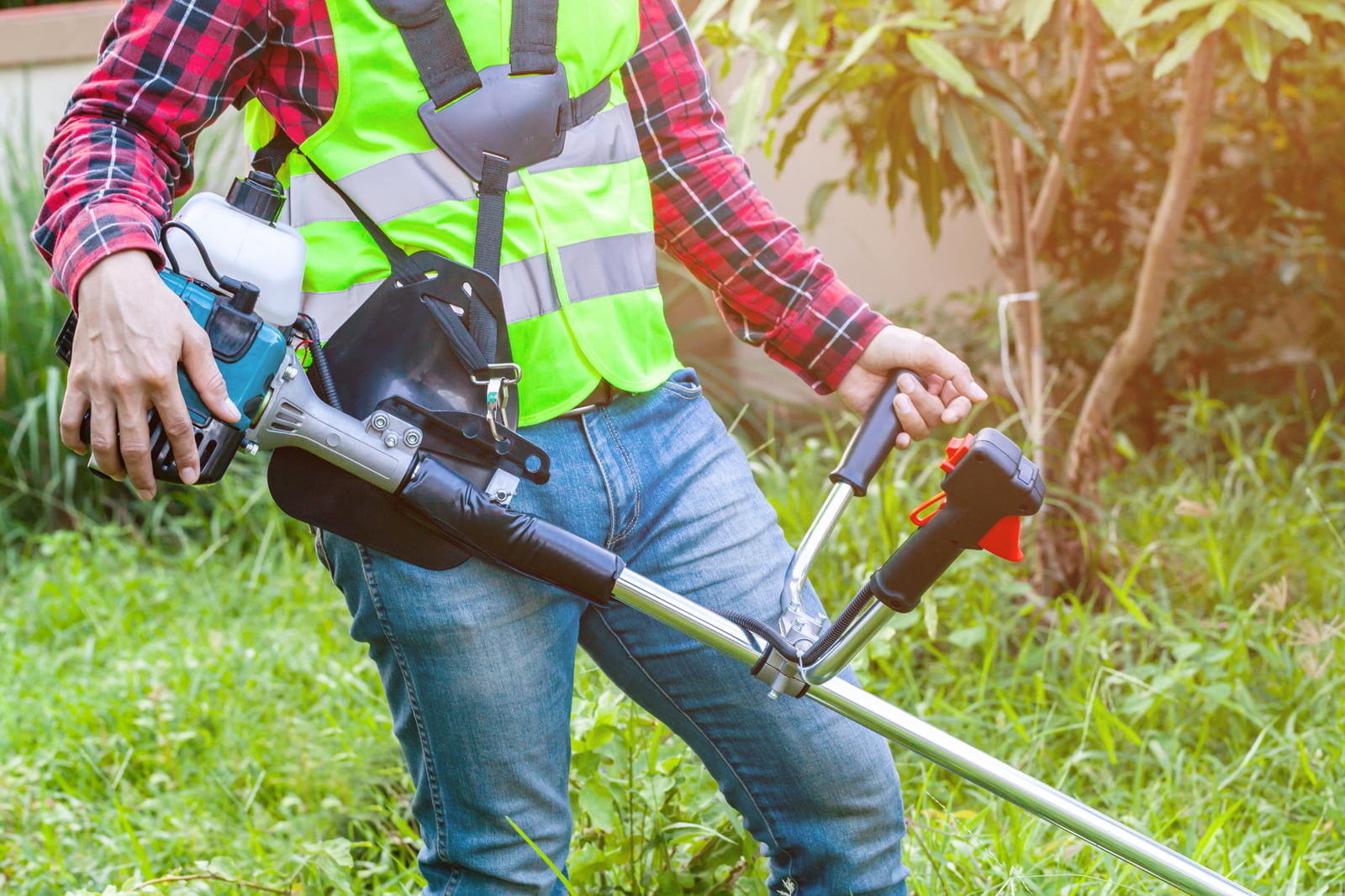 workman holding lawn mower machine cutting grass in garden on morning