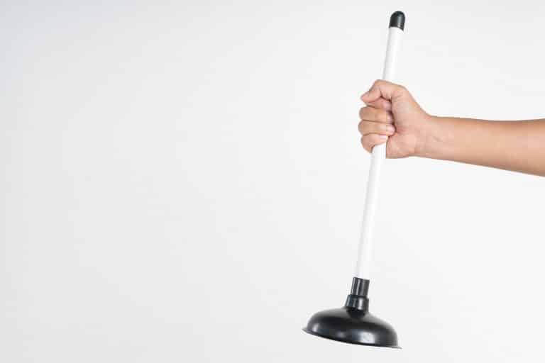 Hand holding toilet black rubber plunger or toilet suction cup for unclog water pipe on white background