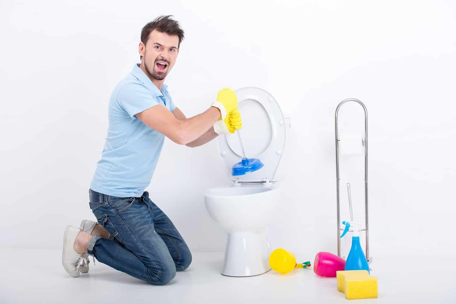 Young man unclogging a toilet with plunger.