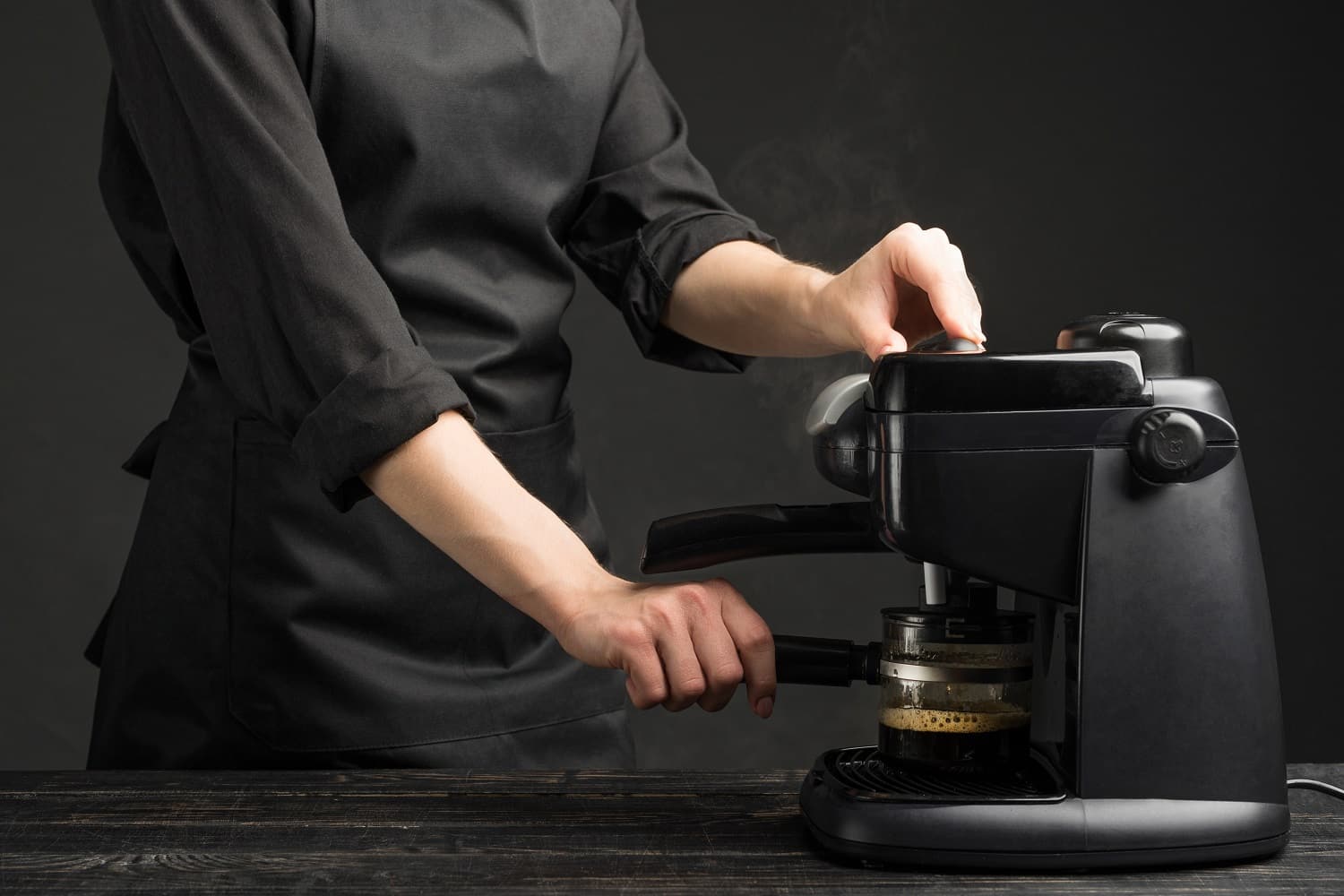 Professional barist with a coffee machine, brews coffee. Against a dark background