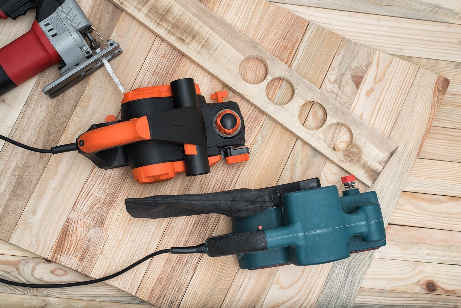 Set of handheld woodworking power tools for woodworking and the workpiece lies on a light wooden background