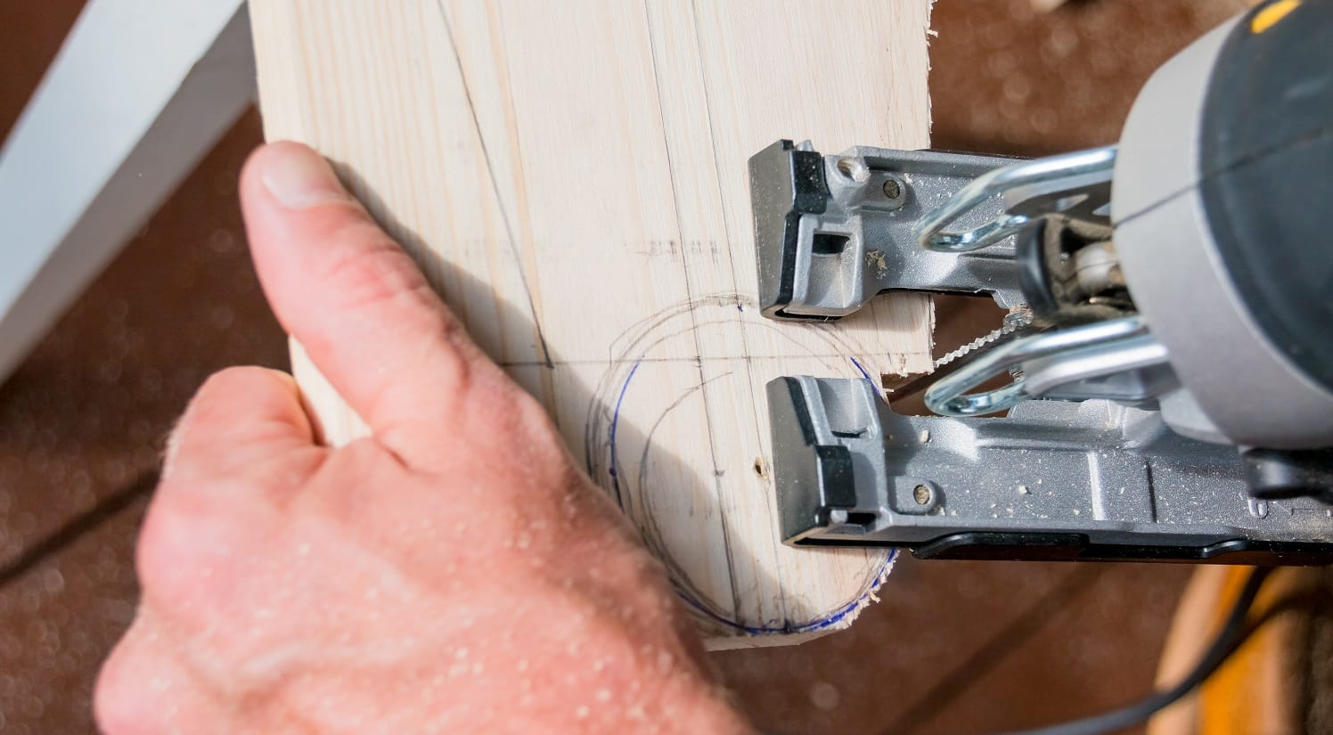 young man carpenter builder working with electric jigsaw and wood