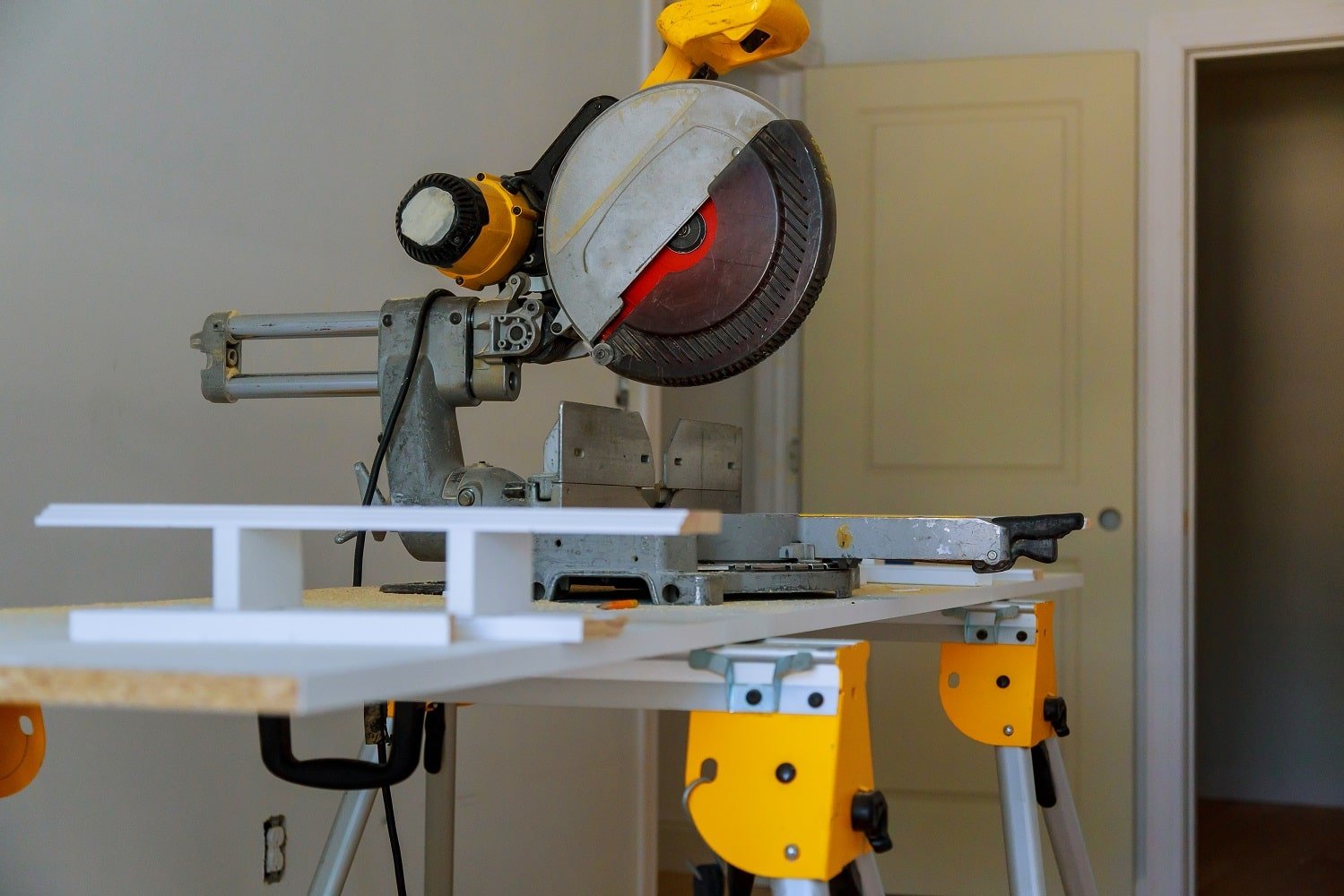 contractor uses a circular saw to cut trim molding Miter Saw on a construction site with a worker in background