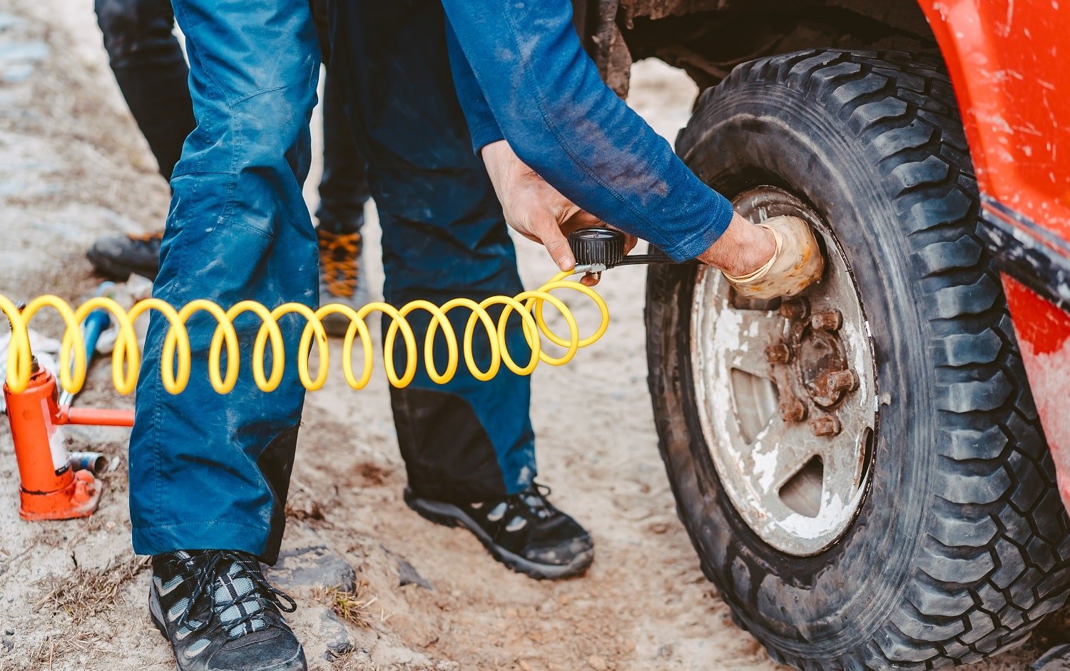 A man pumps air wheel with a compressor on the road