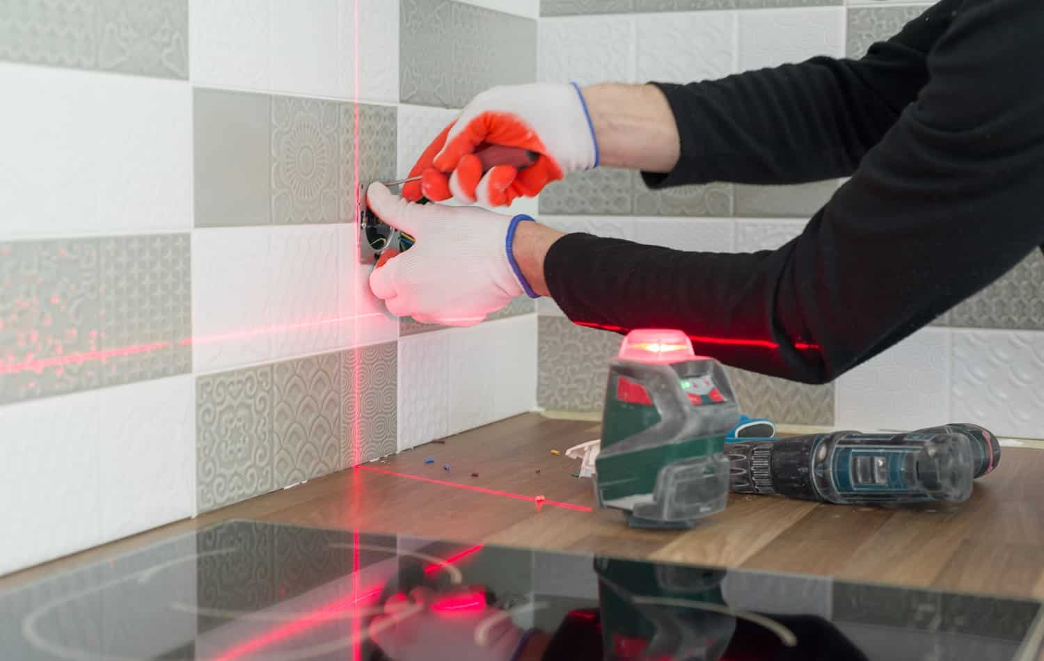 Electrician using infrared laser level to install electrical outlets. Renovation and construction in kitchen.