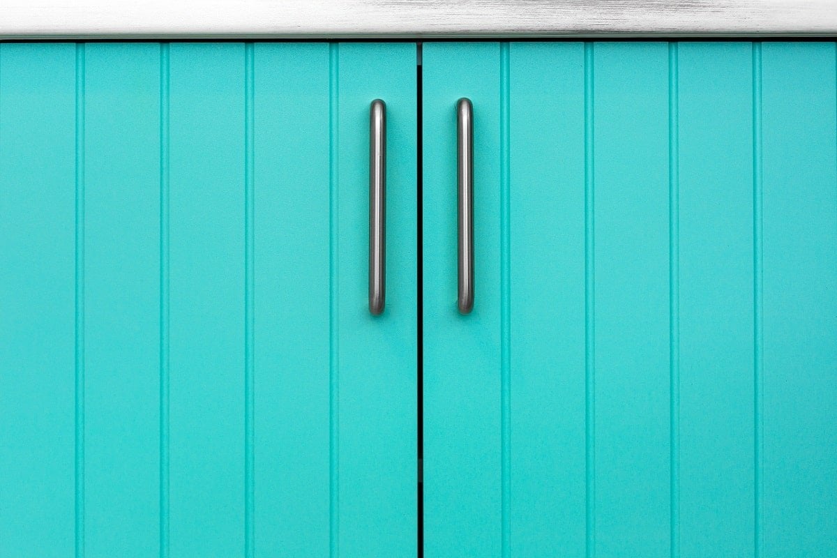 Blue wooden facade of kitchen cabinets made of thin strips with chrome handles.