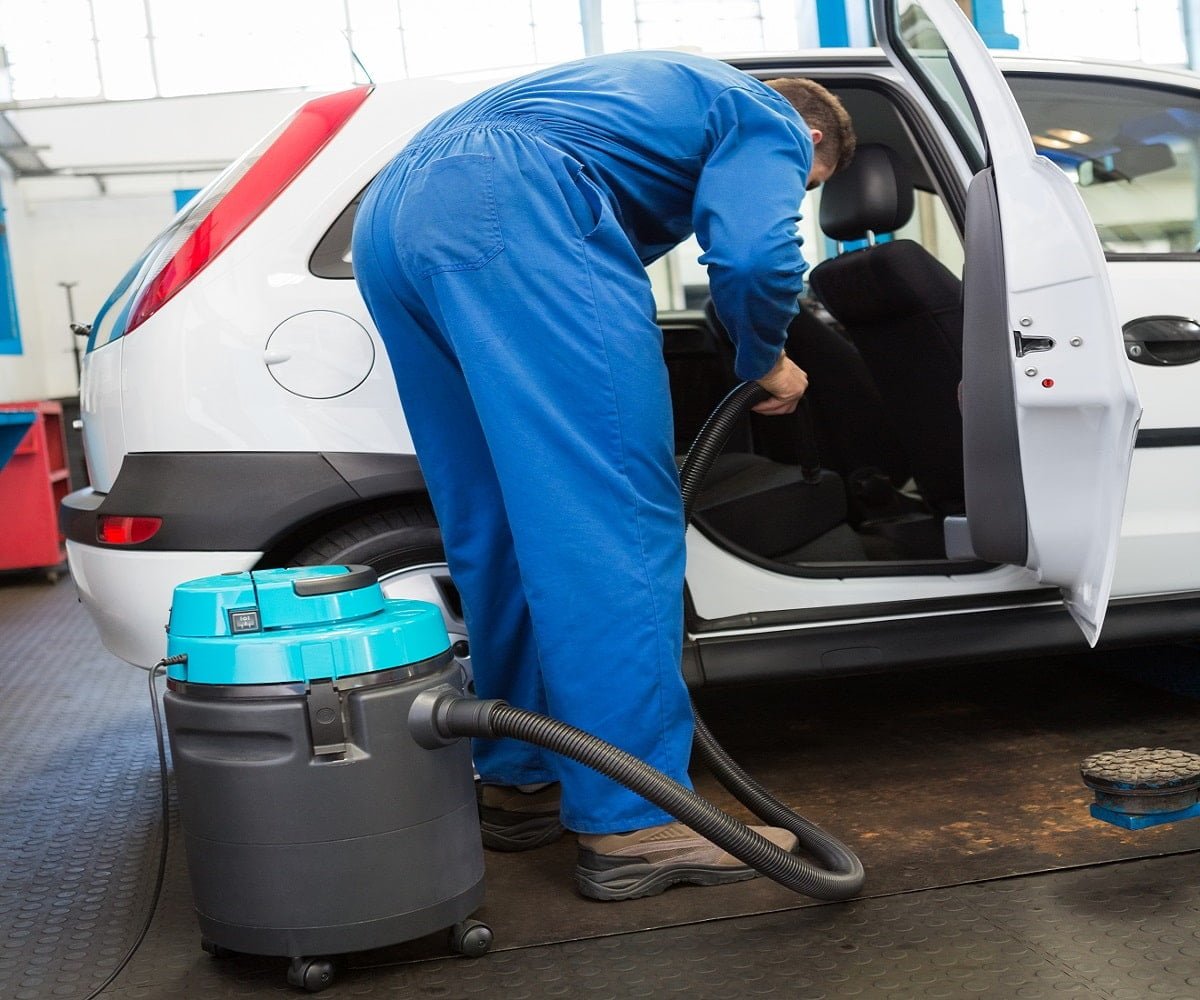 Mechanic vacuuming the car interior at the repair garage