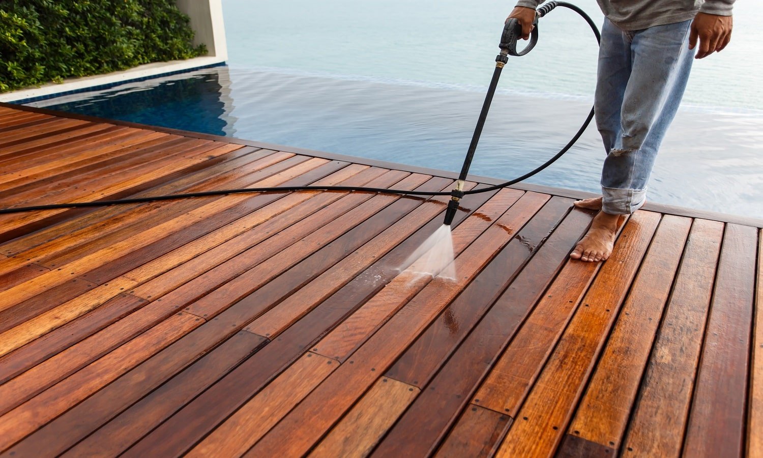 Thai man do a pressure washing on timber