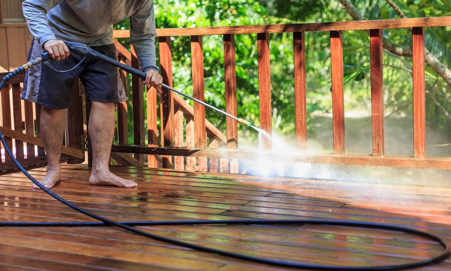 Thai man do a pressure washing on timber