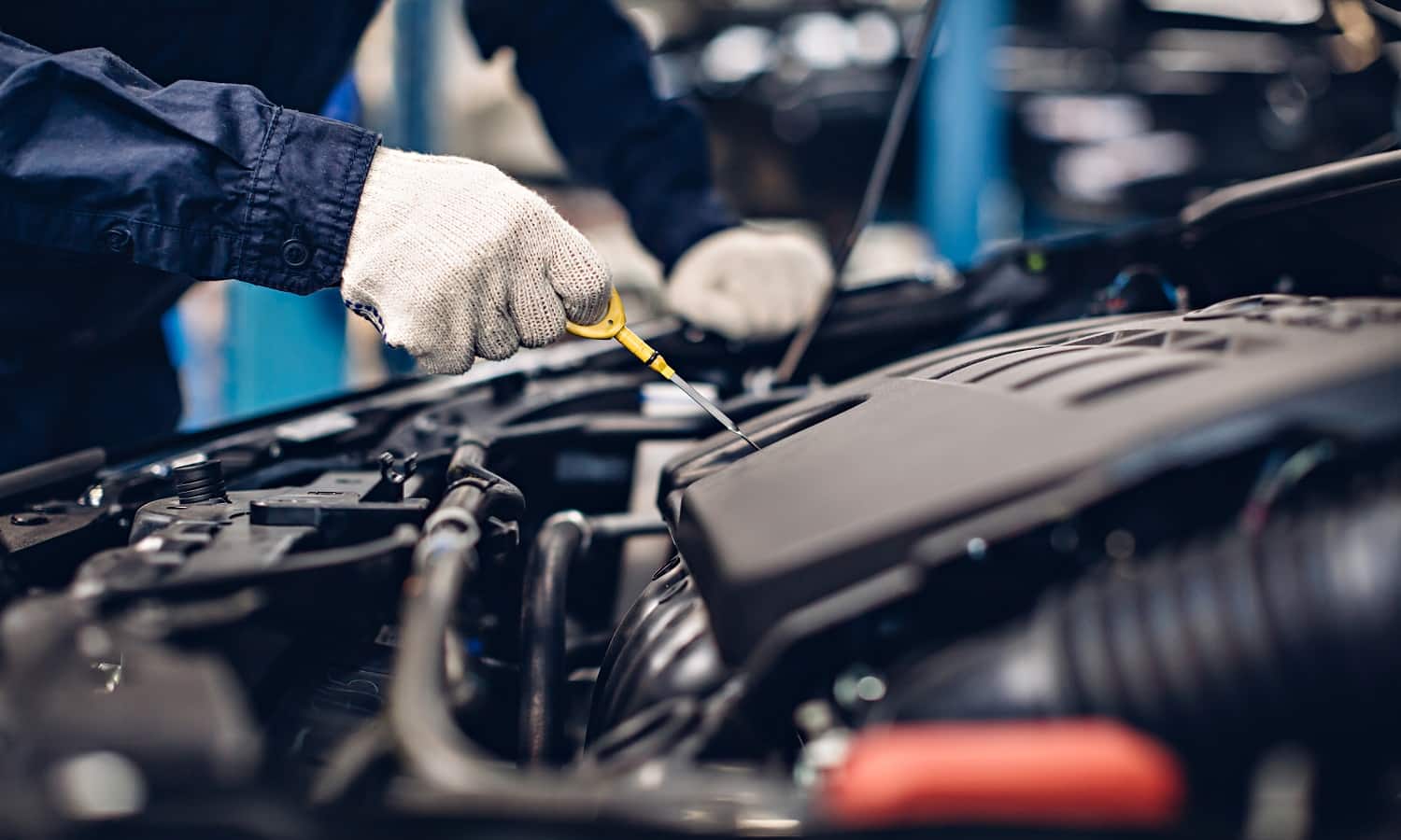 Auto car repair service center. Mechanic checking engine oil level