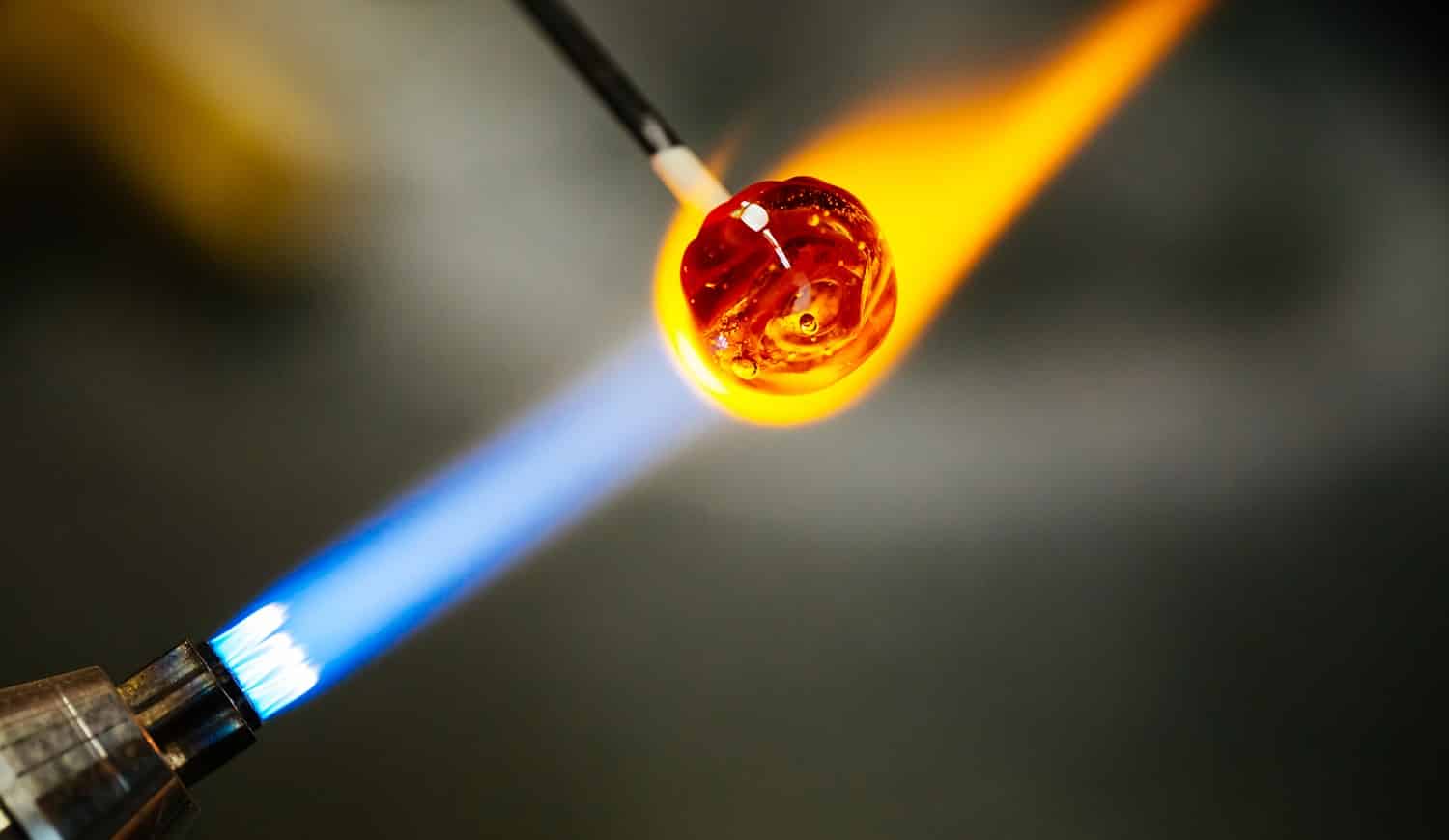 Close-up of glass bead melting in gas-burner fire, craftwork