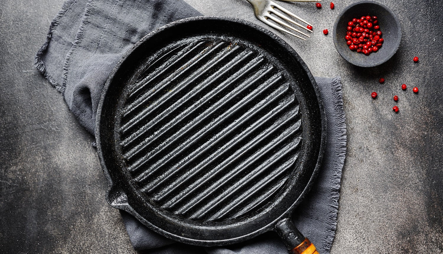 Empty old iron grill pan with napkin on dark background. Cooking concept.