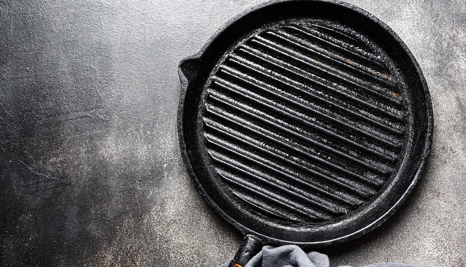 Empty old iron grill pan with napkin on dark background. Cooking concept.