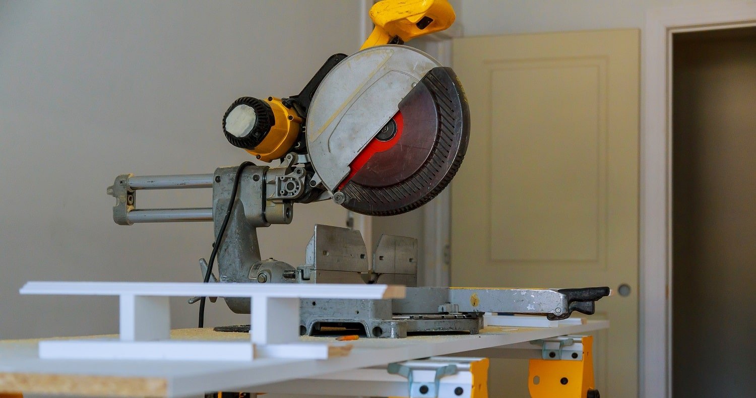 contractor uses a circular saw to cut trim molding Miter Saw on a construction site with a worker in background