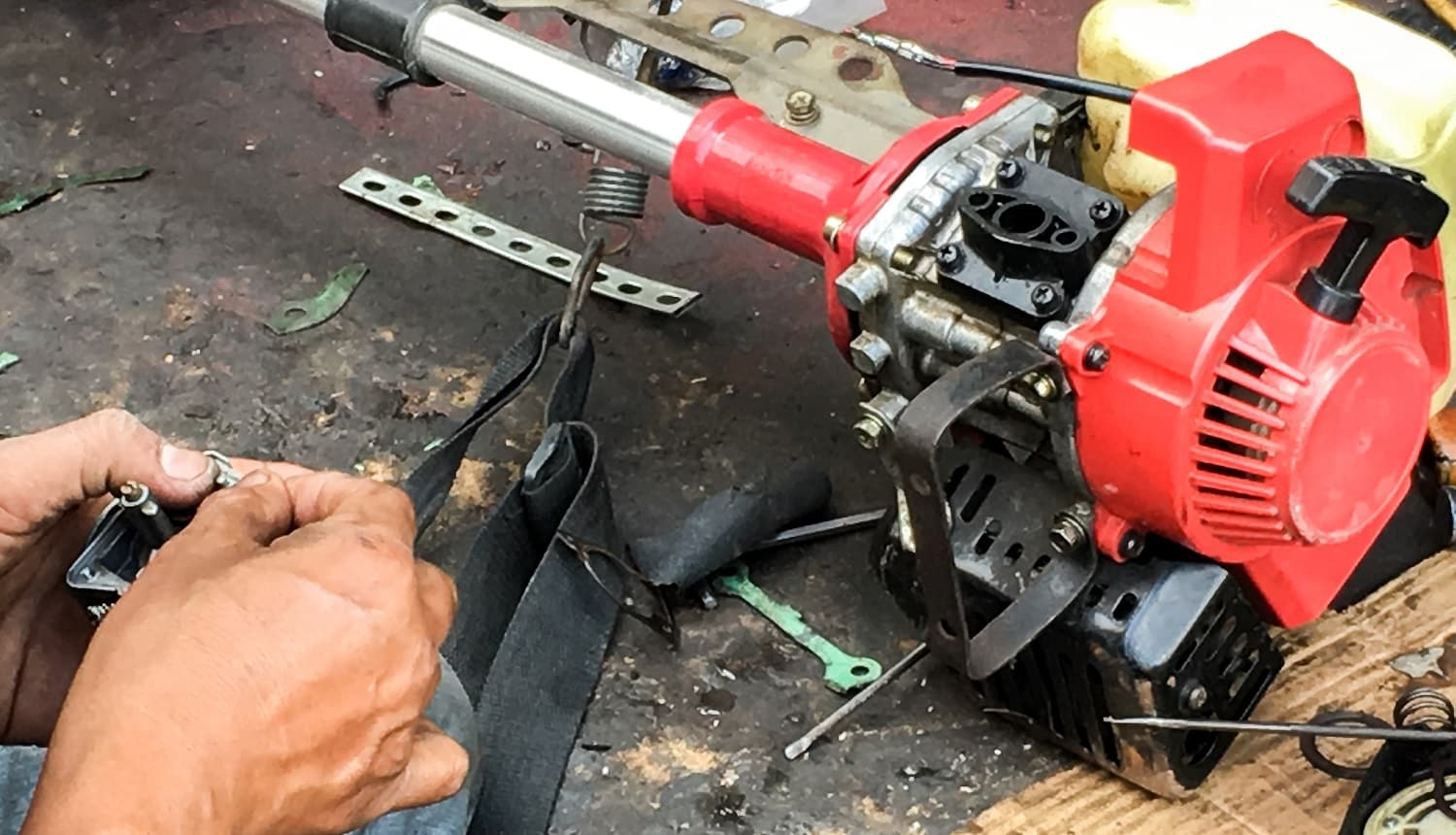 Repairman fixes the lawnmower with tools on the sidewalk.