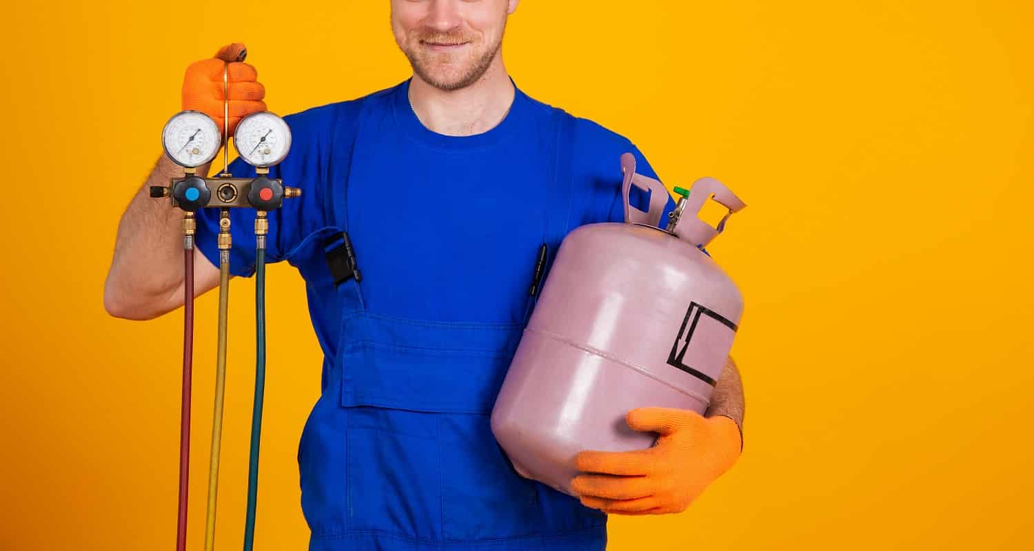 Young cheerful smiling air conditioning specialist. Repair of air conditioners and manometers, measuring equipment for refueling air conditioners. On a yellow background