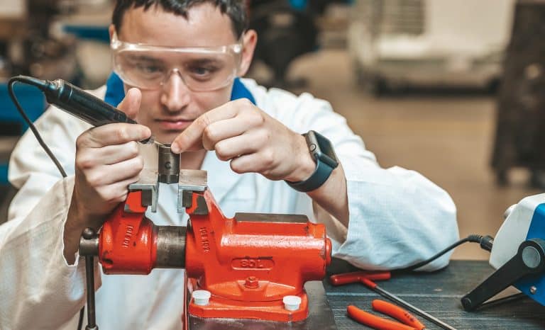 student of technical school on practical exam when working with vise and electric grinder.