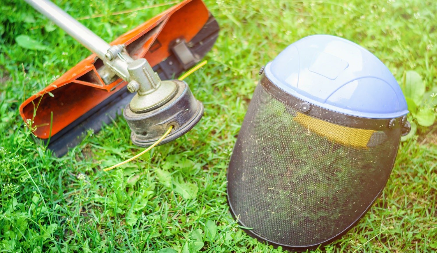 String trimmer and protective face mask on grass