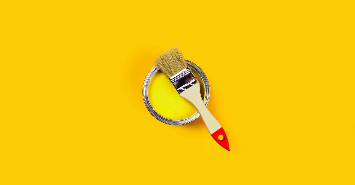 Renovation concept. Yellow background with paint can and brush. Flat lay, top view, copy space.