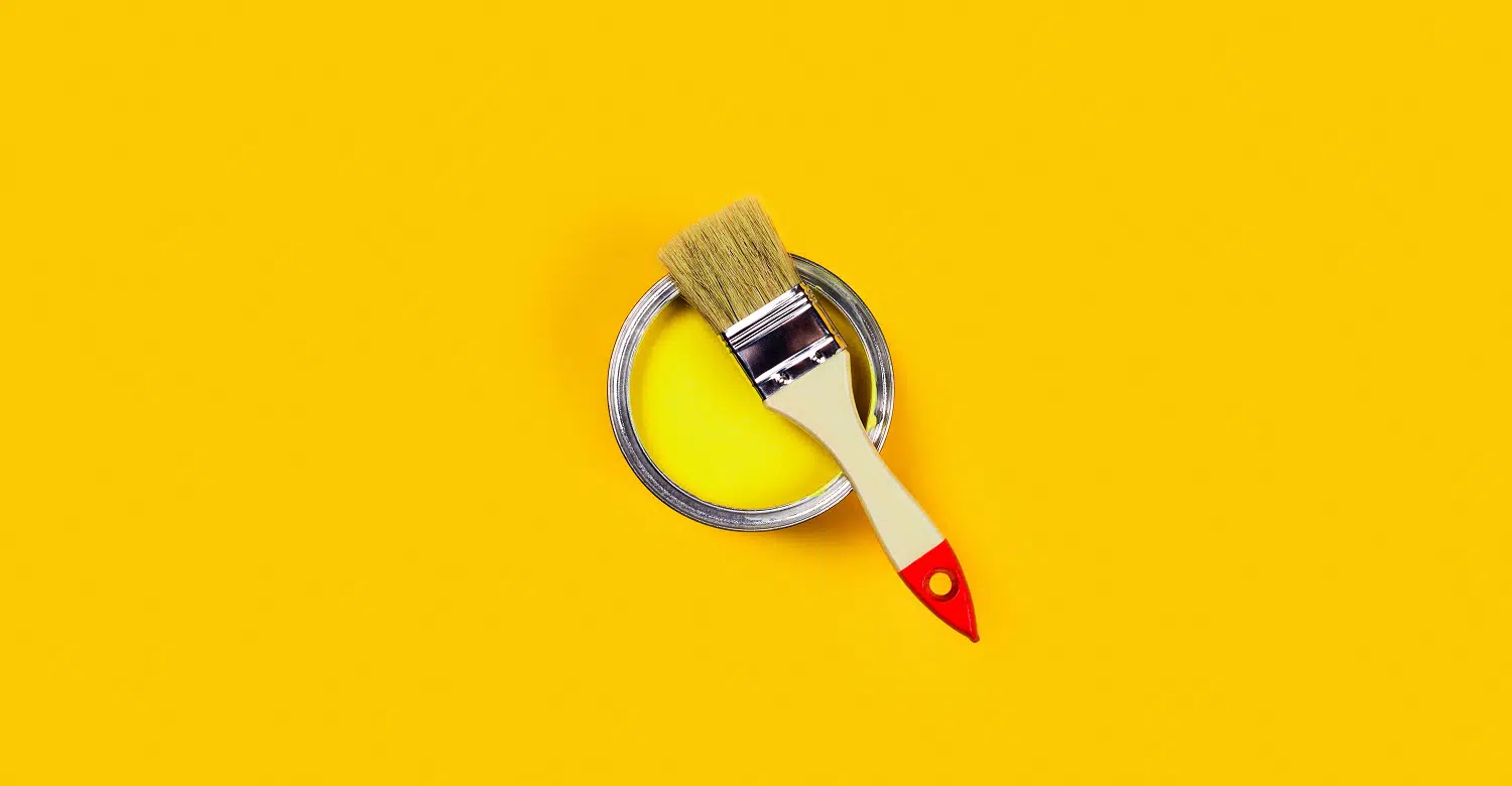 Renovation concept. Yellow background with paint can and brush. Flat lay, top view, copy space.