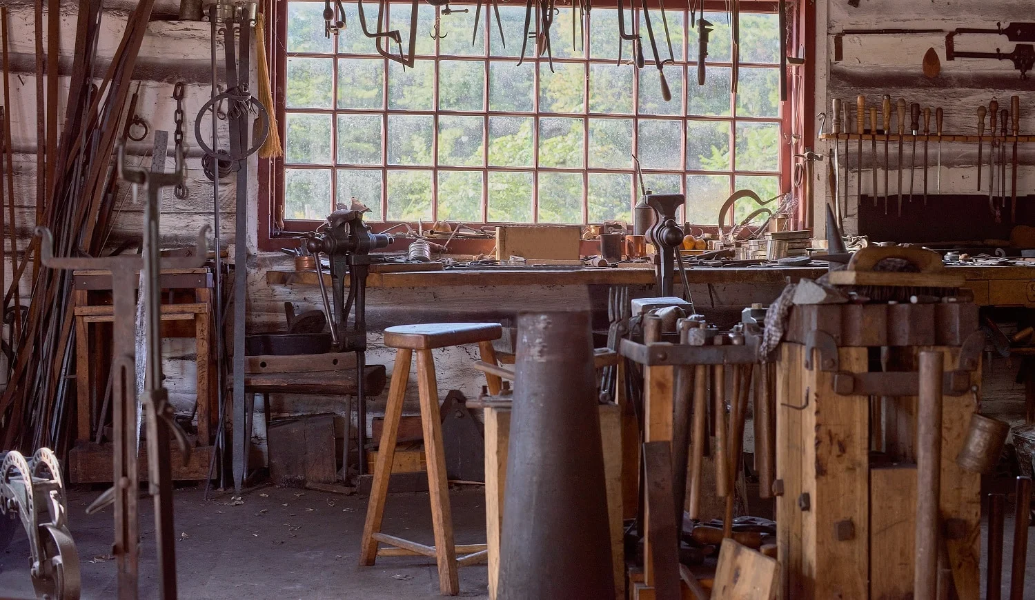 large table by the window Old vintage craftsman's workshop blacksmith with a jaw vise and other tools.
