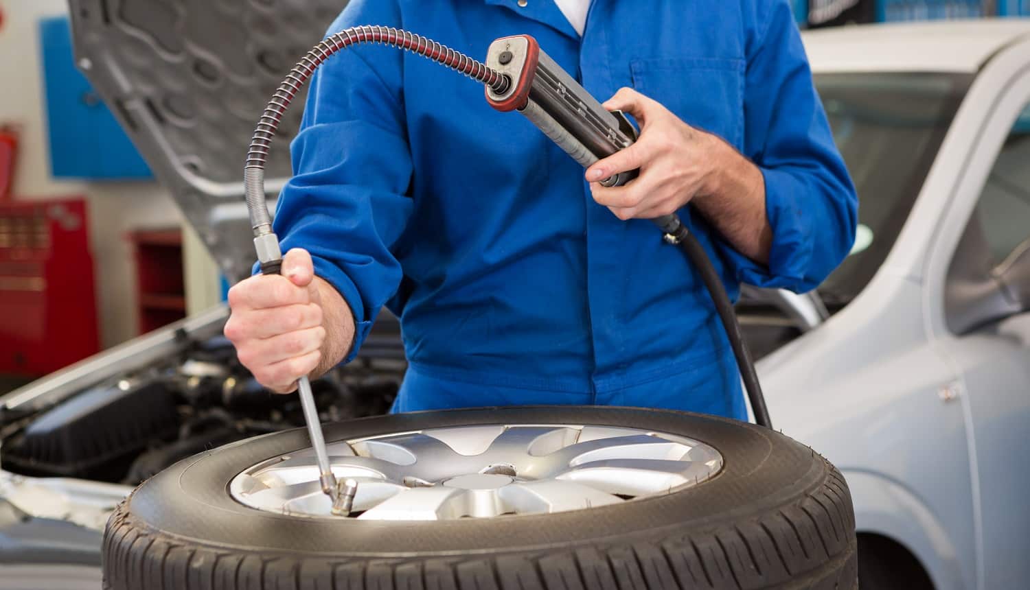 Close up of mechanic inflating the tire at the repair garage