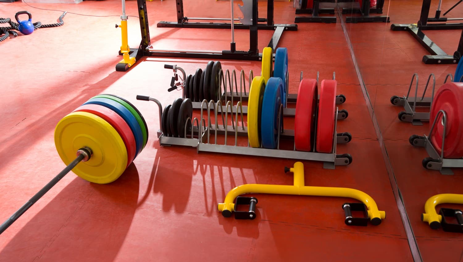 Crossfit fitness gym weight lifting bar colorful equipment on red floor