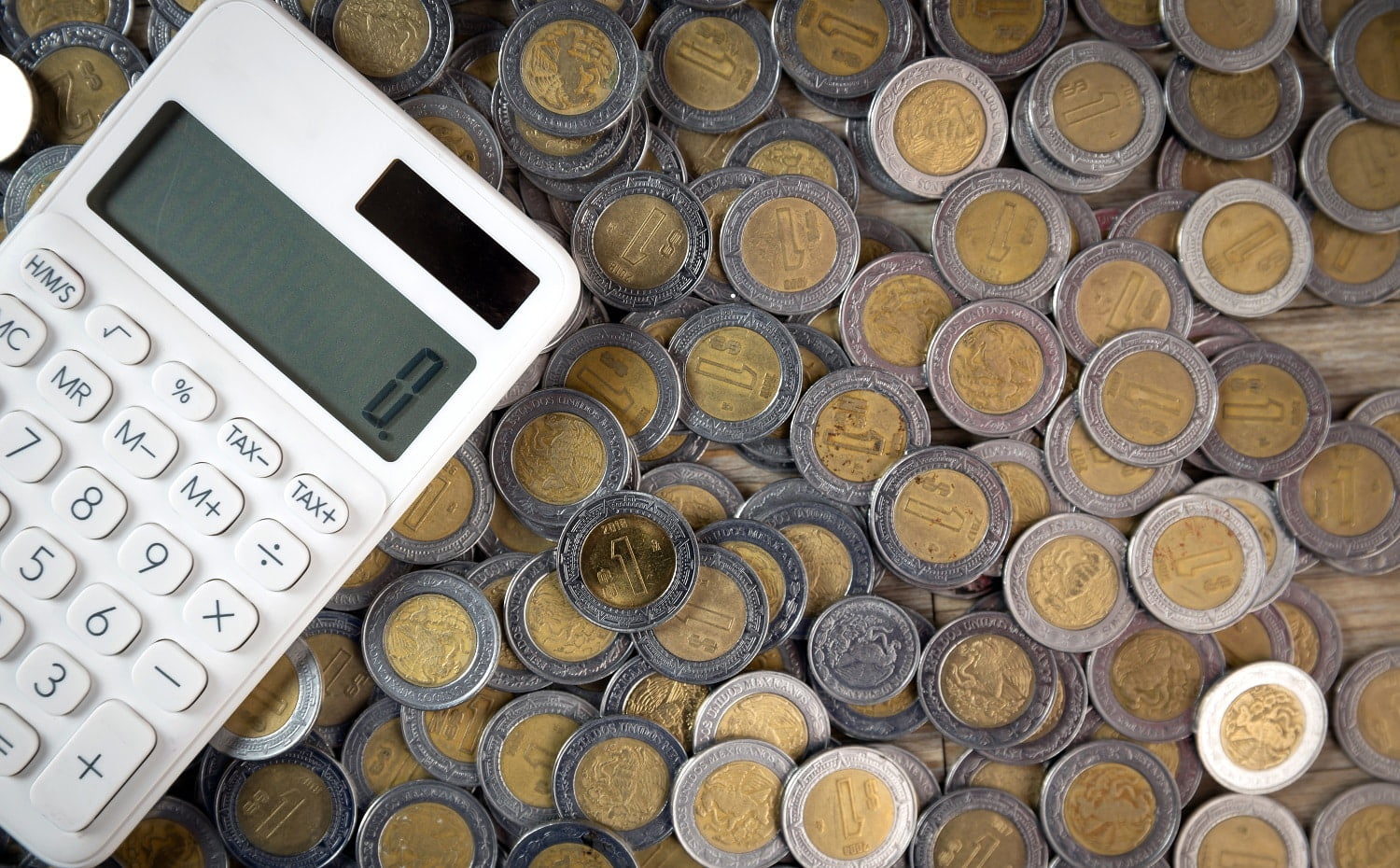finance mexican coins in heap with shot from above with calculat