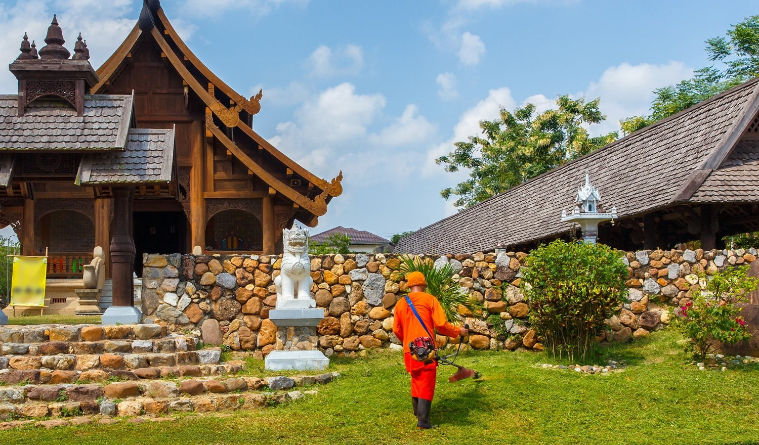 Monk cutting grass in garden around the temple in countryside of northern Thailand