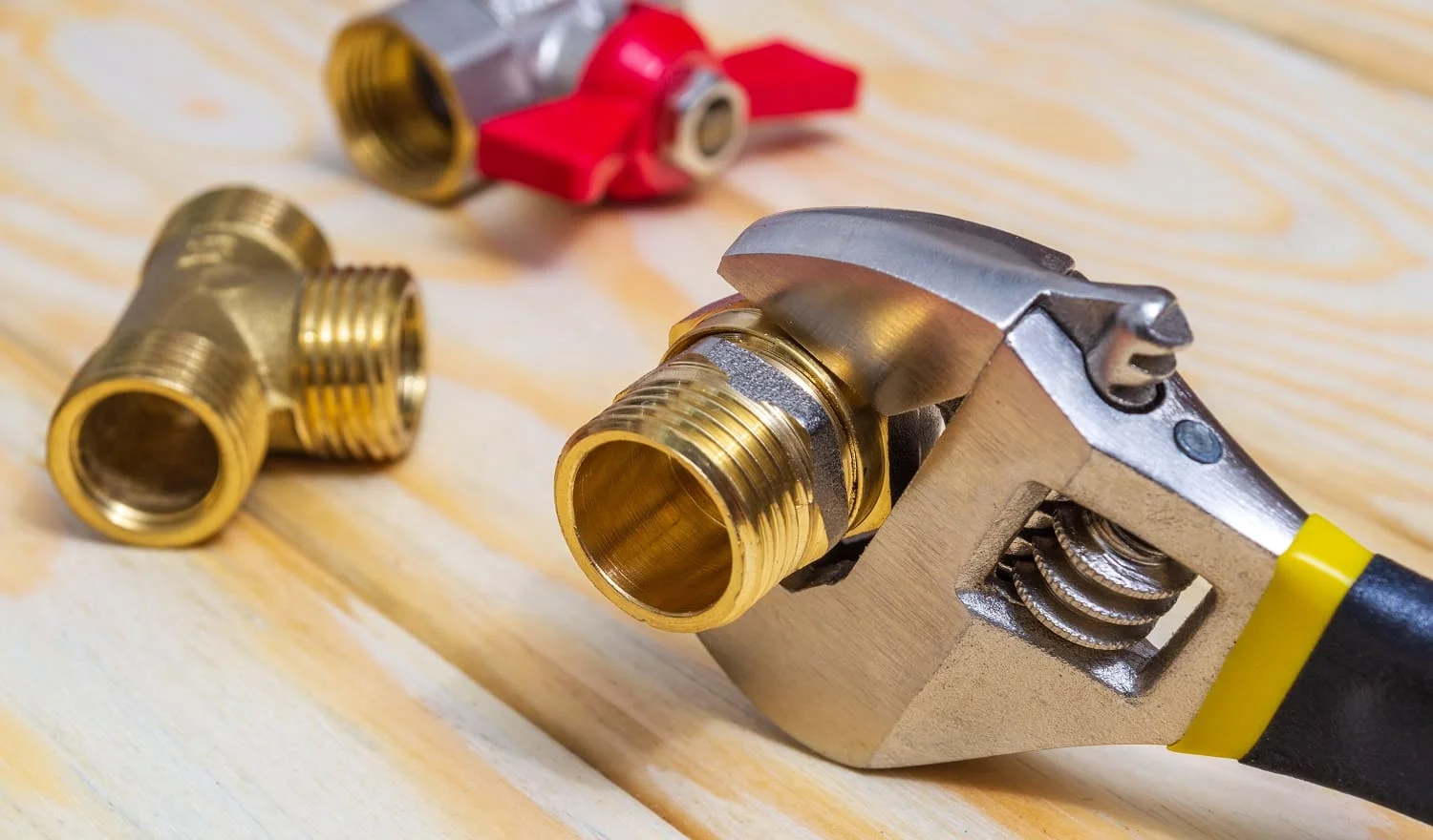 Plumbing fitting and adjustable spanner closeup on a wooden boards during repair or replacement of spare parts