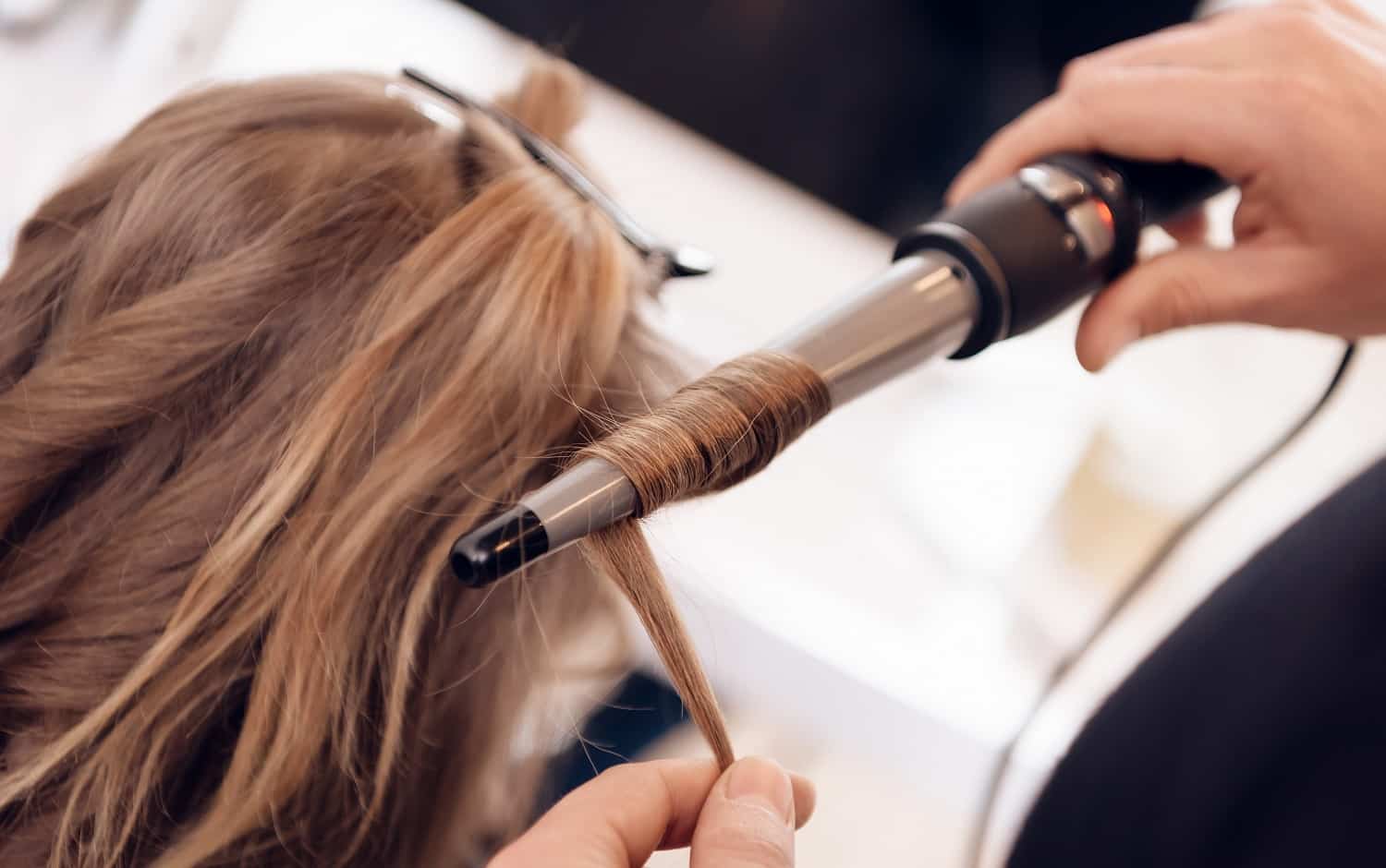 Close up. Brown hair woman does curling hair in beauty salon