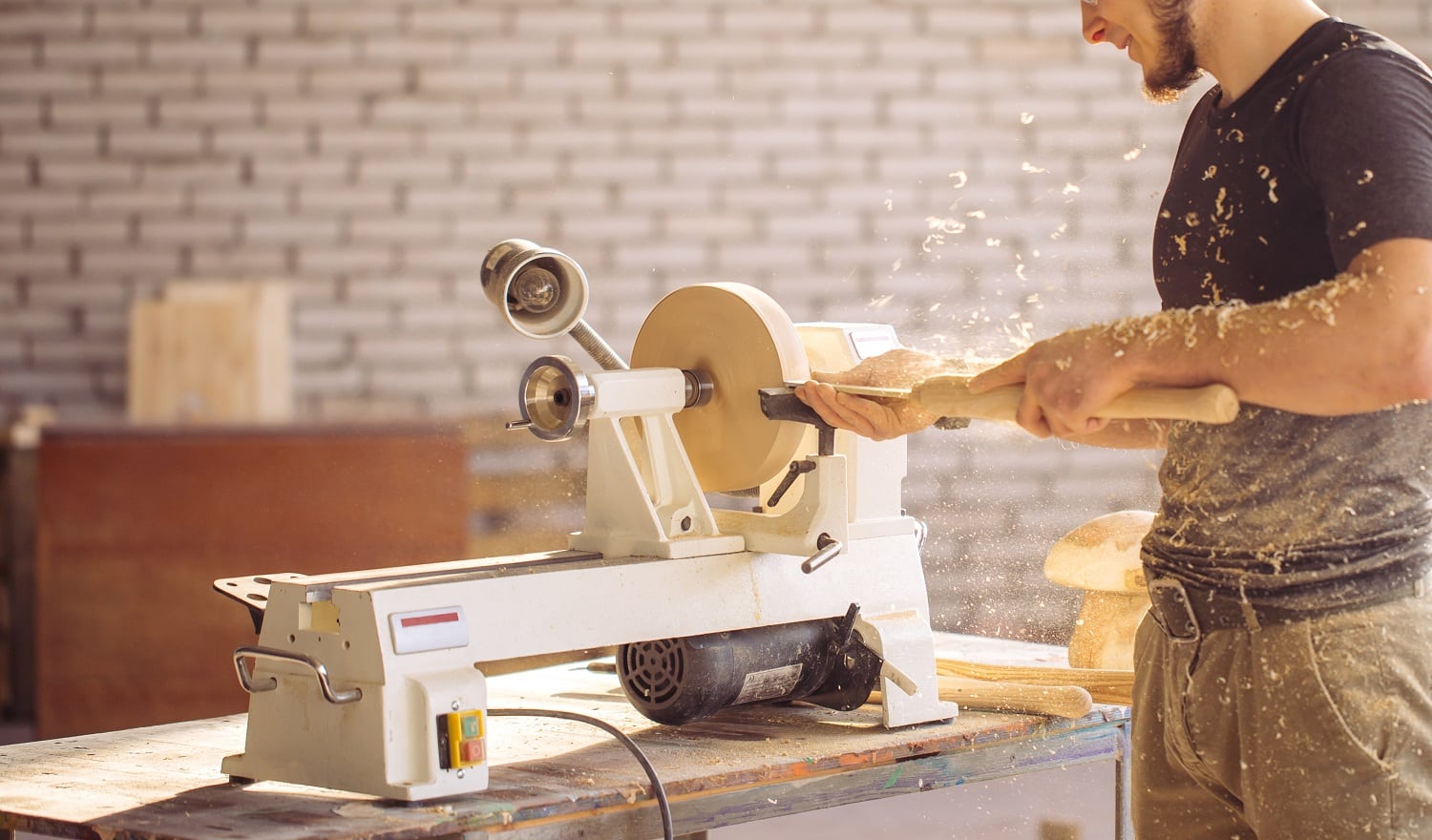 Young carpenter processing wooden plank on special woodworking machine