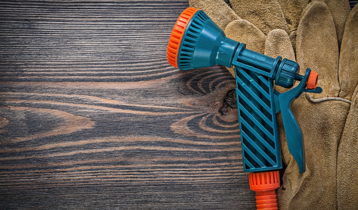 Water sprayer protective gloves on wooden board agriculture concept.