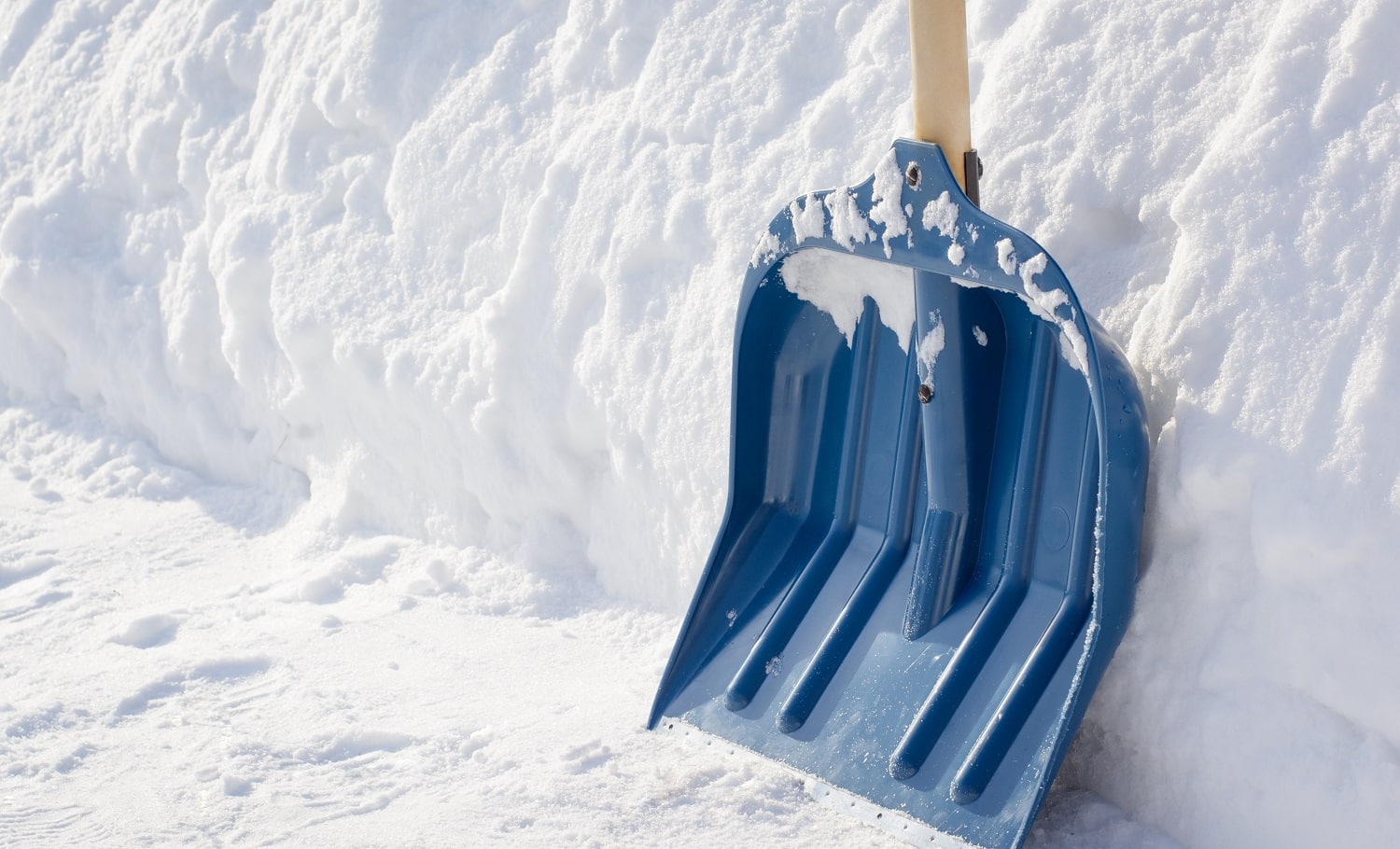 Snow shovel with a wooden handle after cleaning sidewalk in the street