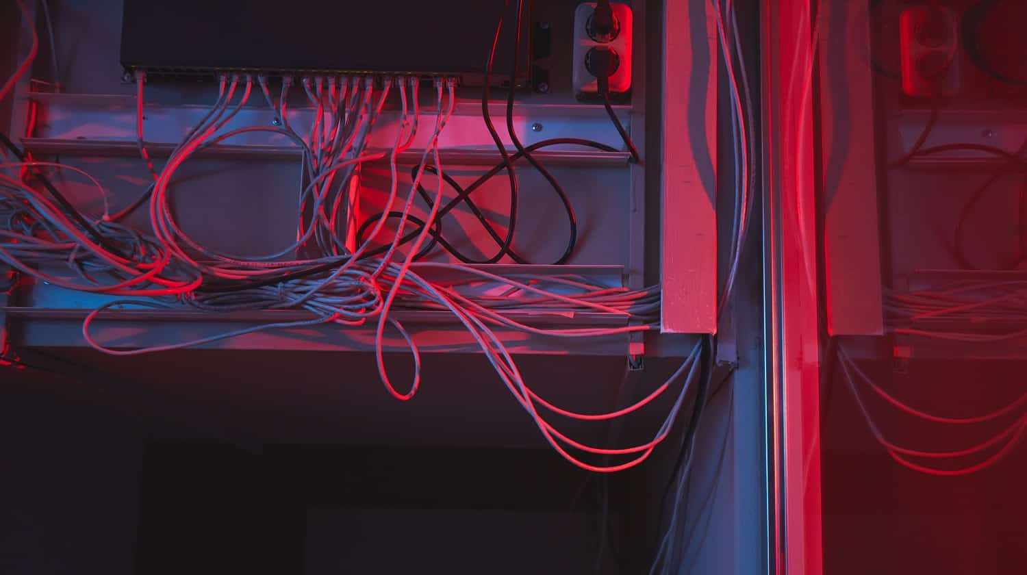 Close-up of network hardware hub with cables plugged into socket placed on wall in dark server room