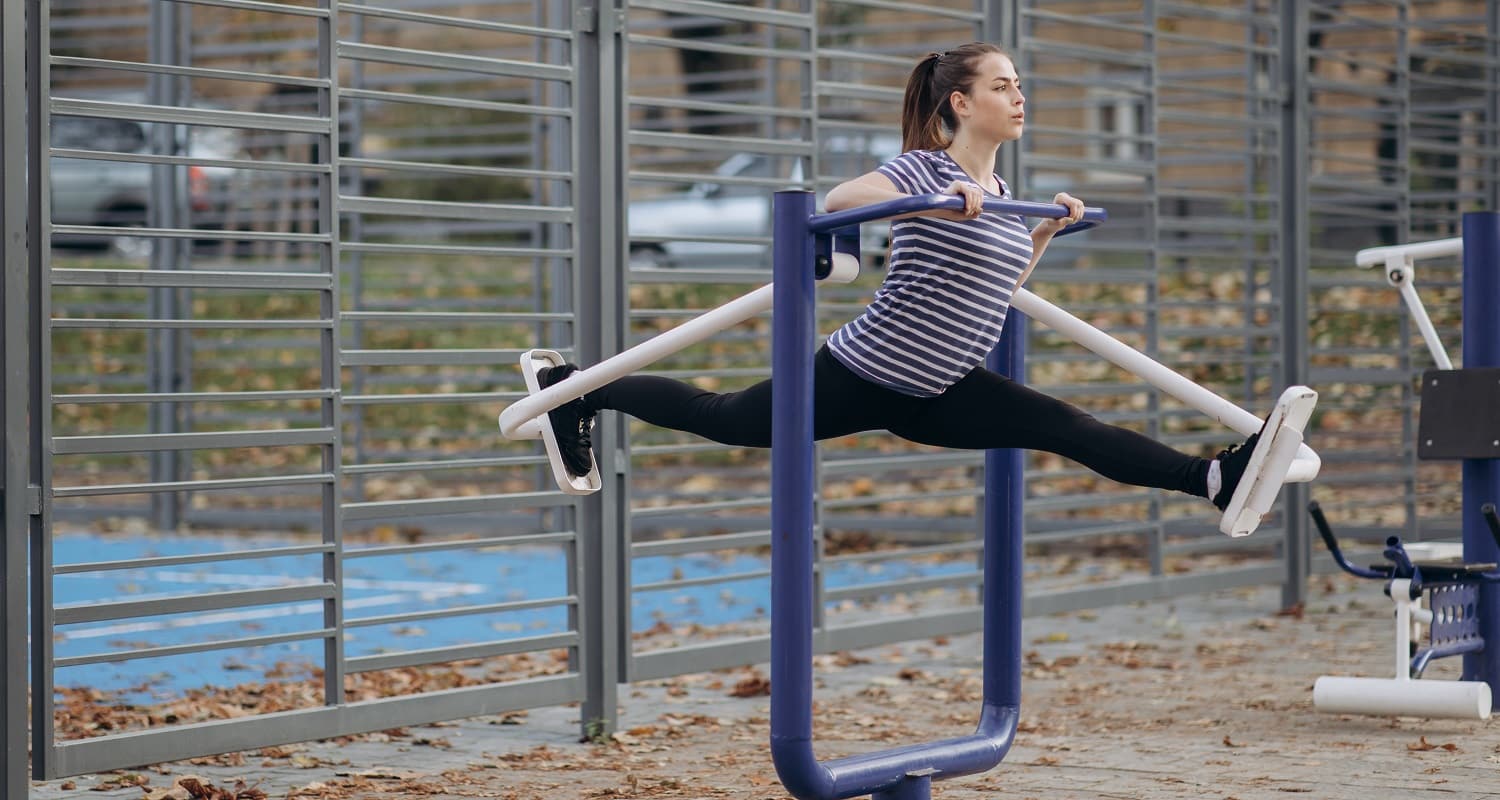 Girl perform daily fitness workout. Young sportive woman do walking exercises at outdoor gym, using cross trainer machine. Healthy lifestyle concept