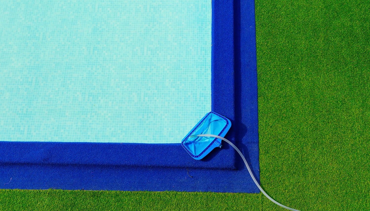Top view cleaning net at on the edge of the pool is green and blue artificial grass.