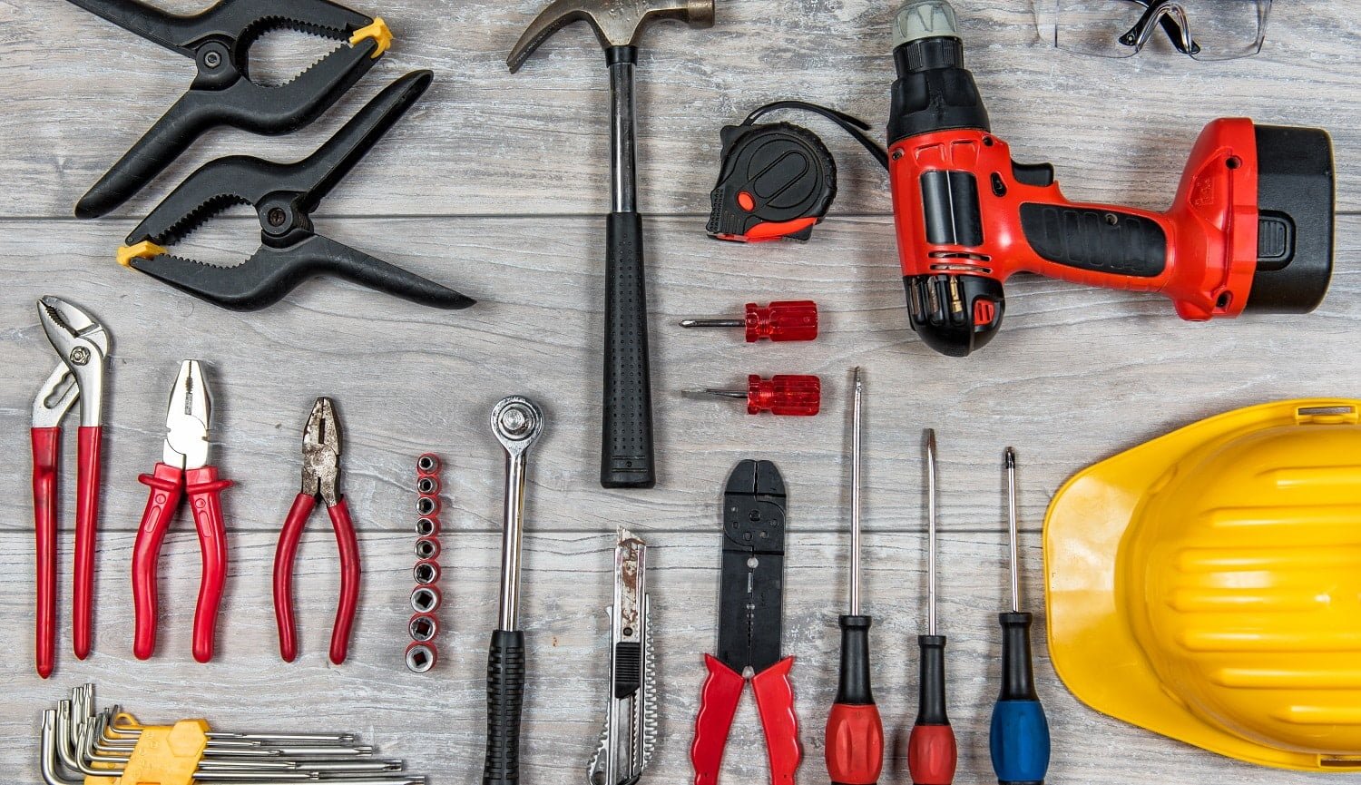 Various construction, DIY hand tools lies in knolling organization on a rustic wooden table, desk or workbench.