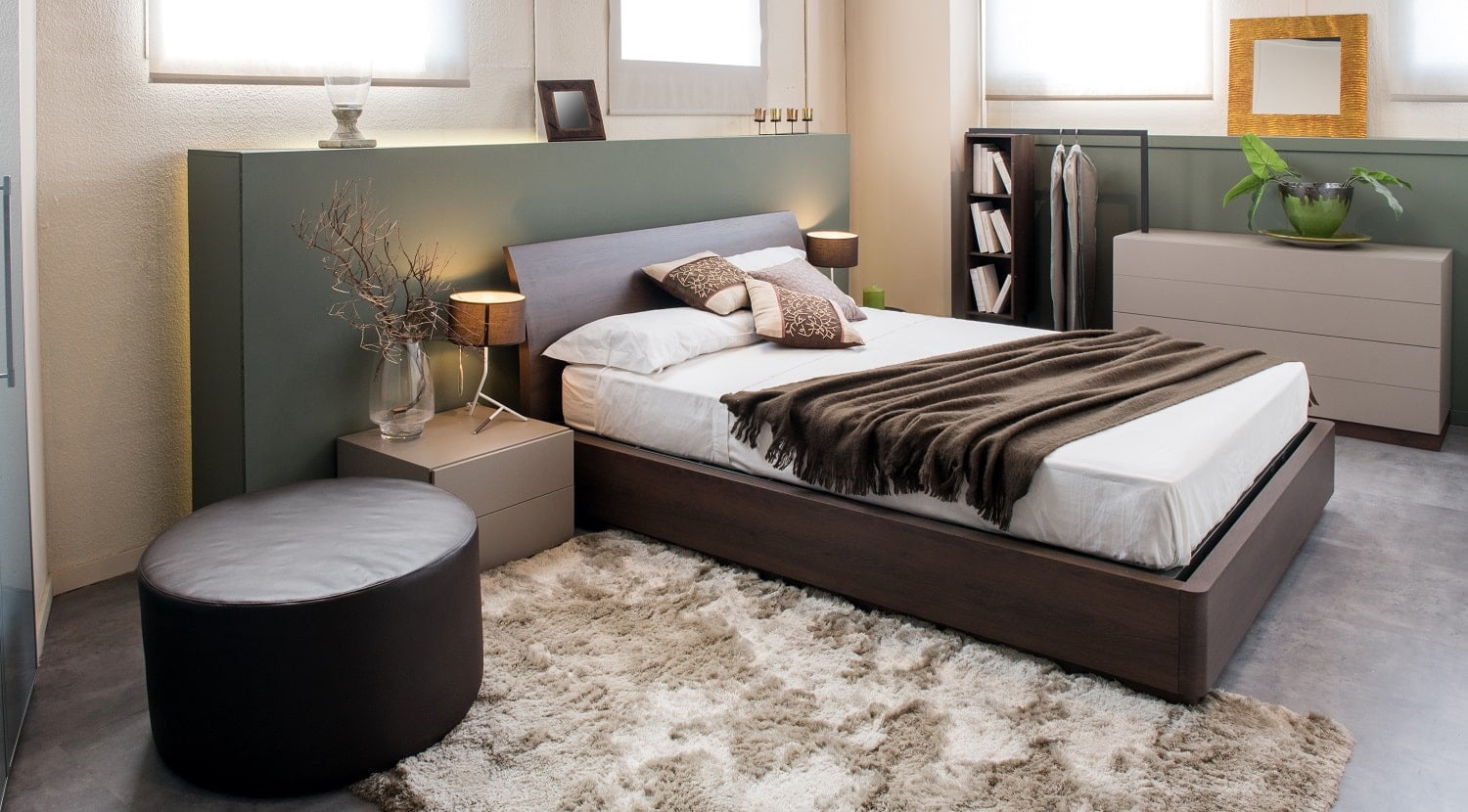Modern luxury brown monochrome bedroom interior with large headboard above a double beds with cabinets, ottoman and built in wardrobe
